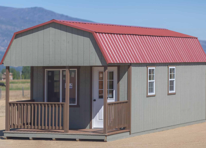 Gray hunting cabin with red metal roof.