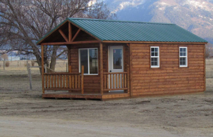 Portable wooden hunting cabin with metal roof.