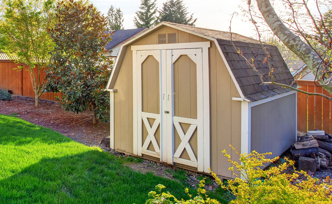 Tan storage shed in backyard.