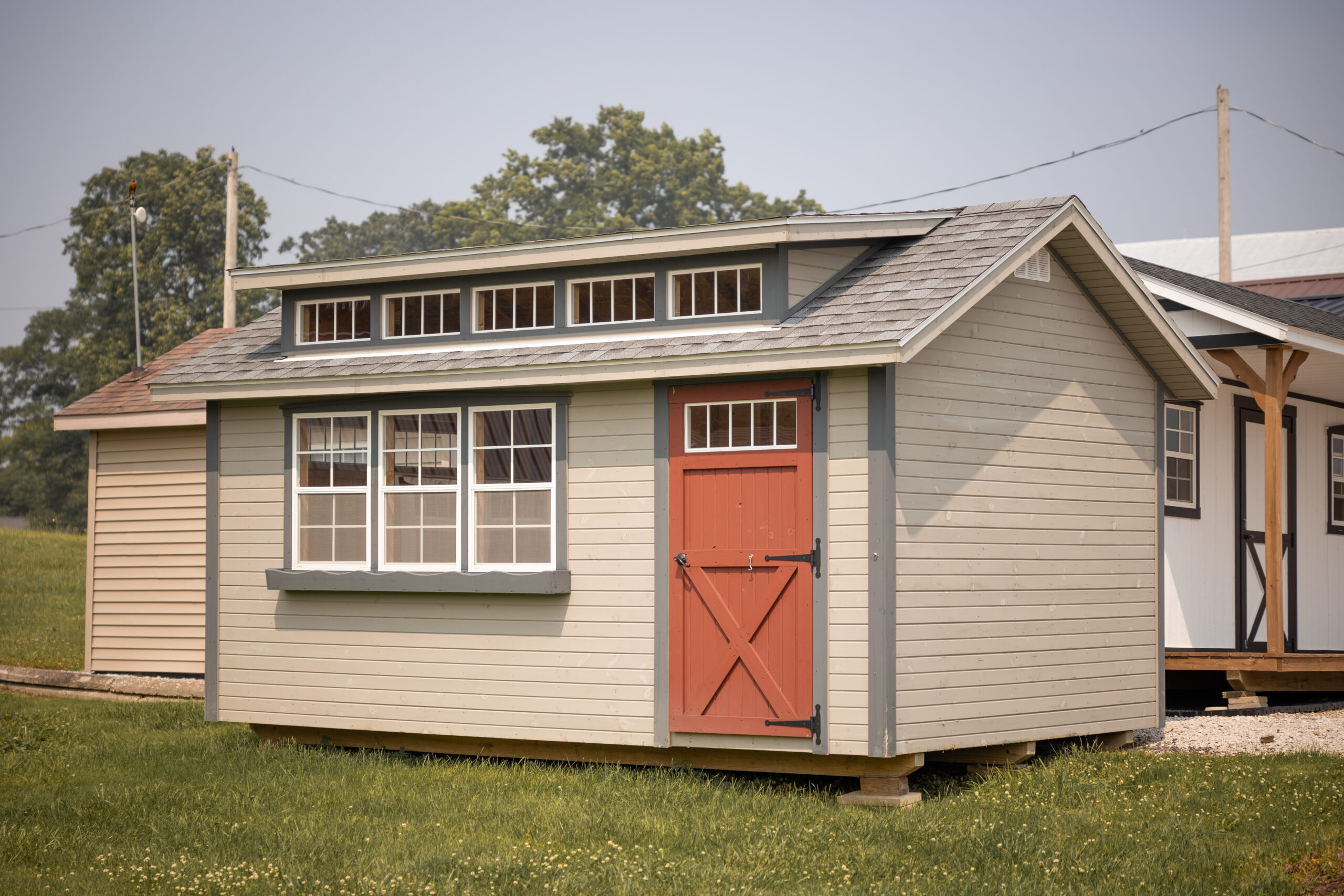 Rent To Own Tan shed with red door and dormer